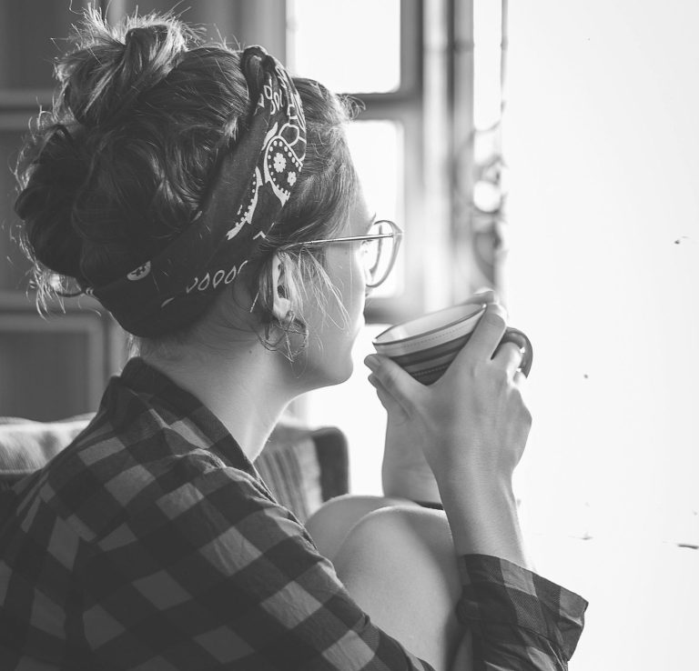 Woman drinking tea while staring into space, appearing contemplative and emotionally introspective, reflecting personal growth challenges.