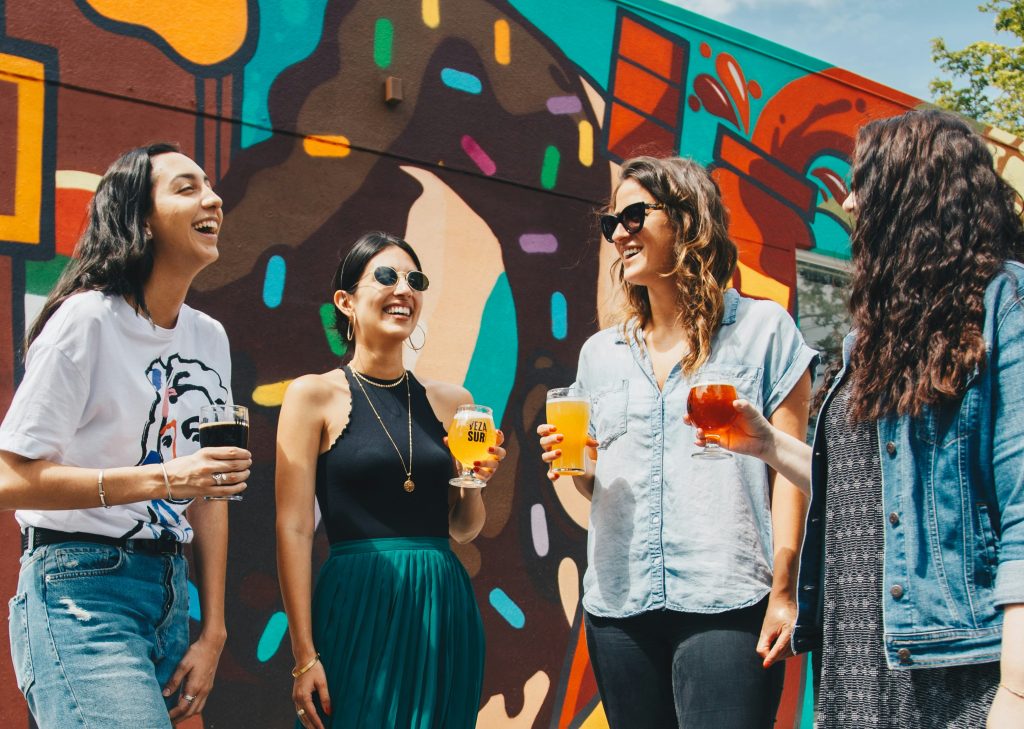 Group of friends chatting and laughing over drinks, showing social connection, support, and healthy interpersonal relationships.