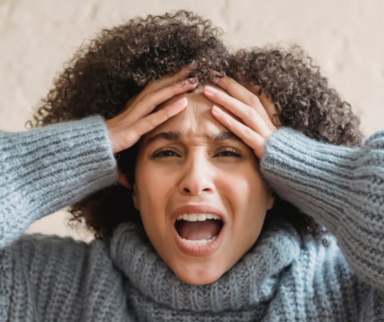 Woman screaming at work with hands on her head feeling stressed and overwhelmed by work and life responsibilities.
